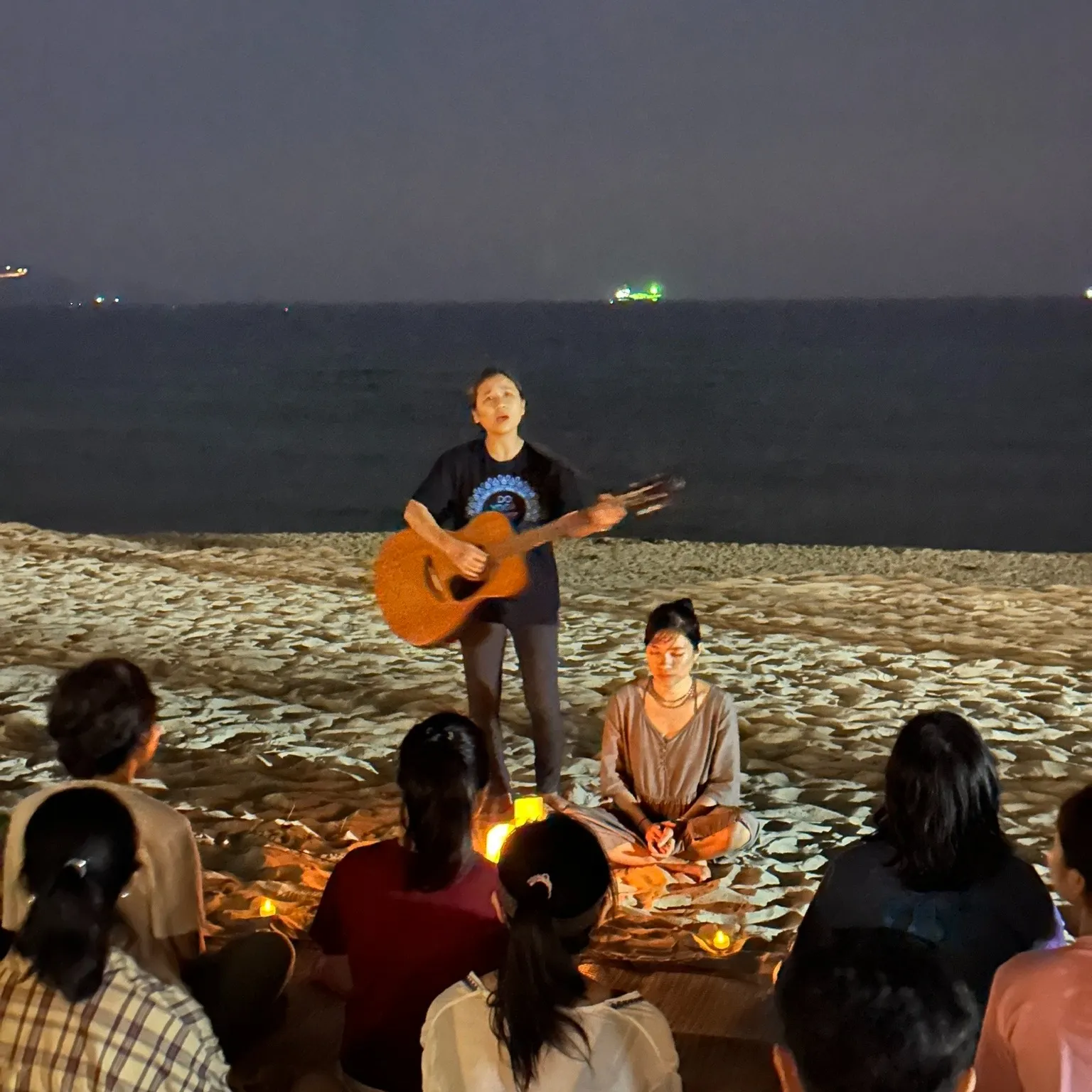 People singing together on the beach at night.