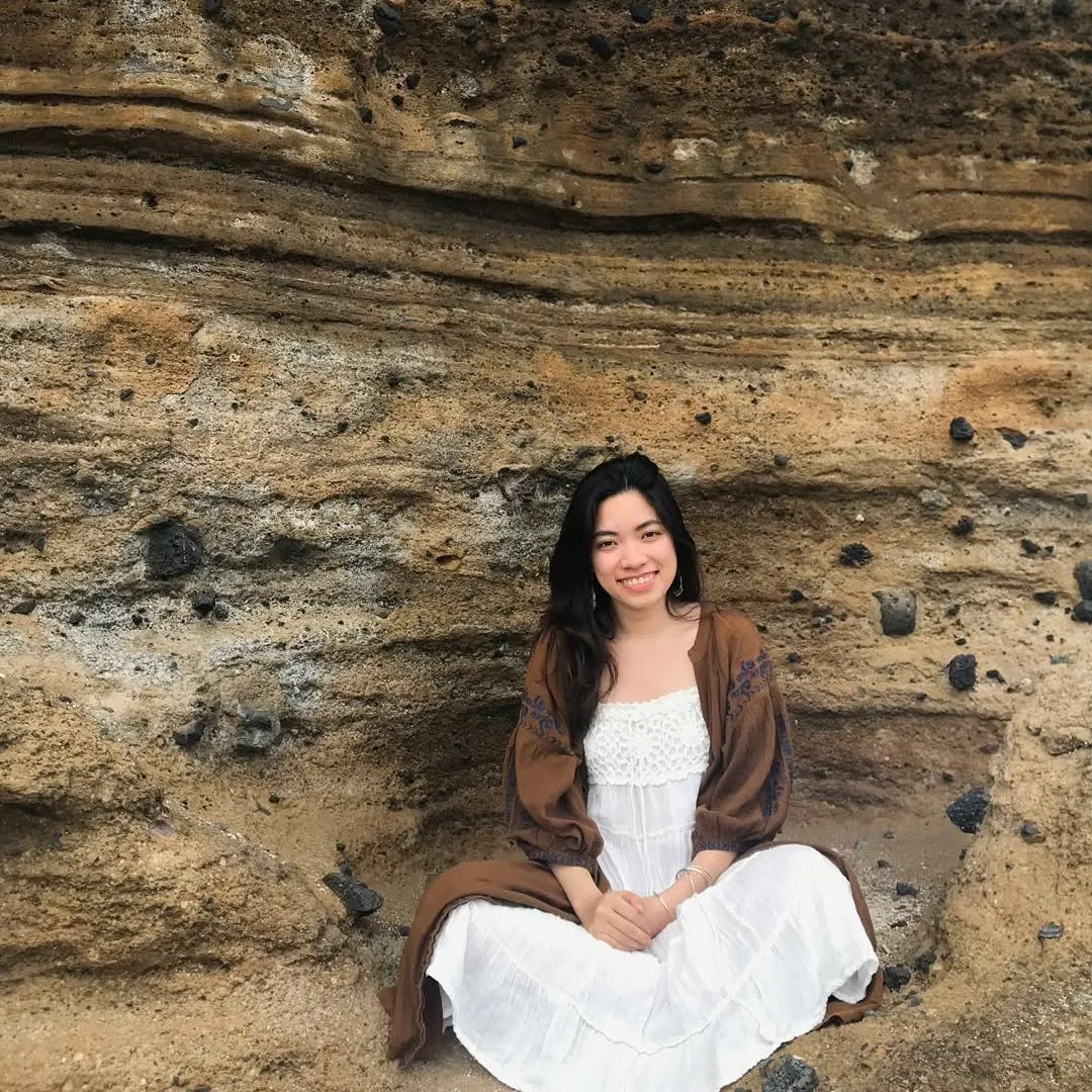A person sitting quietly on rocks outdoors.