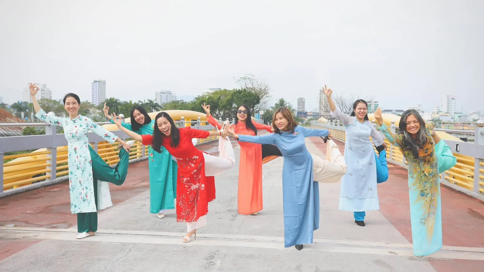 Bảy người mặc áo dài cùng tạo dáng vũ công trên một cây cầu.