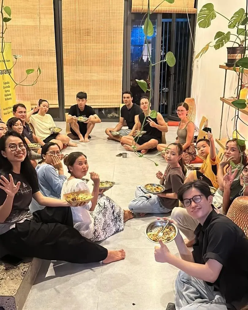 Mọi người ngồi trên sàn ăn tối chay cùng nhau và mỉm cười.