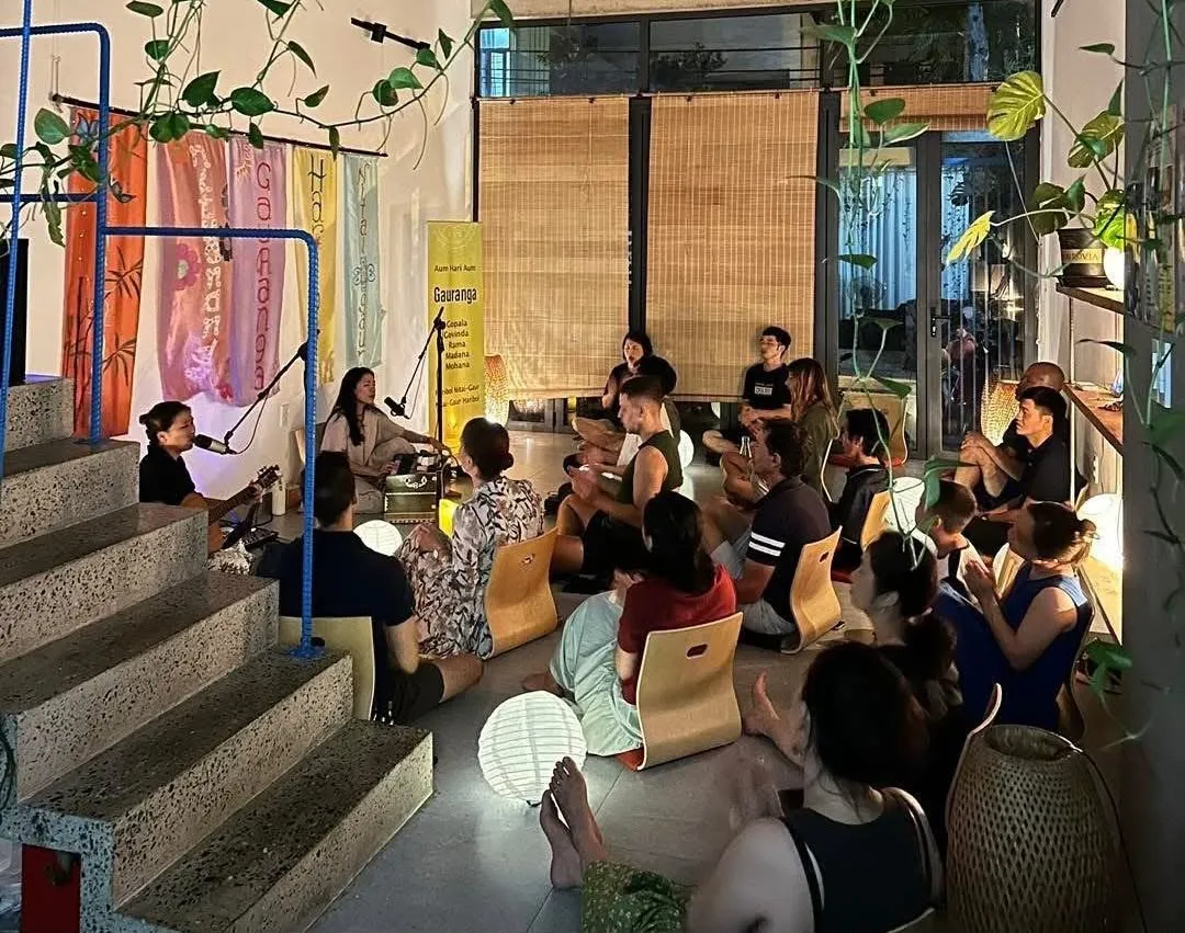 Một buổi thiền nhạc buổi tối, mọi người ngồi trên sàn lắng nghe người chơi guitar và harmonium.