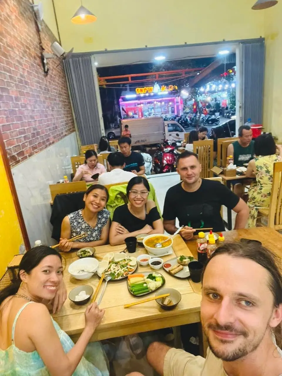 Bạn bè chụp ảnh tự sướng bên bữa tối chay ở nhà hàng.